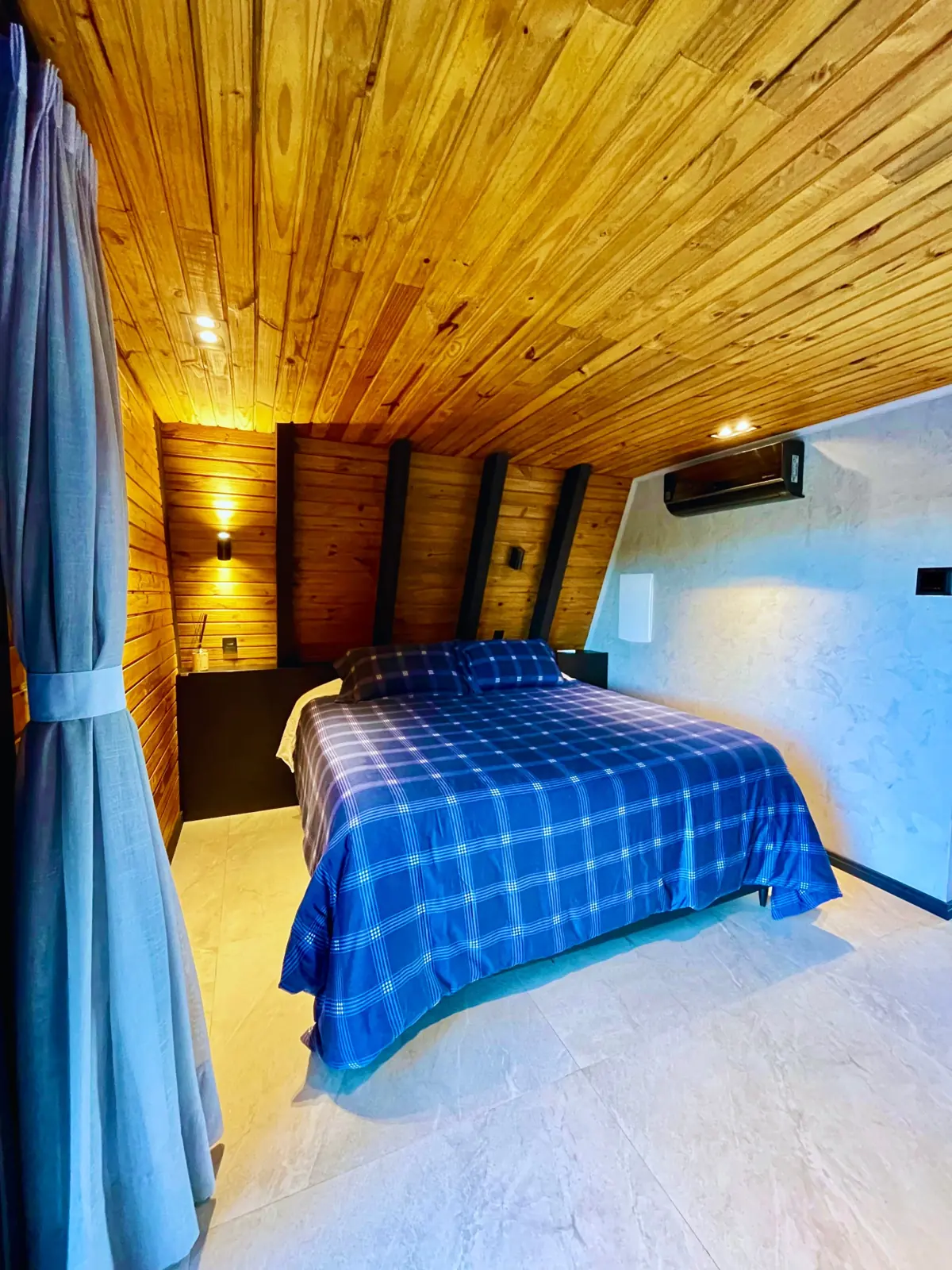 Quarto com cama king, forro de madeira, iluminação indireta e ar-condicionado
