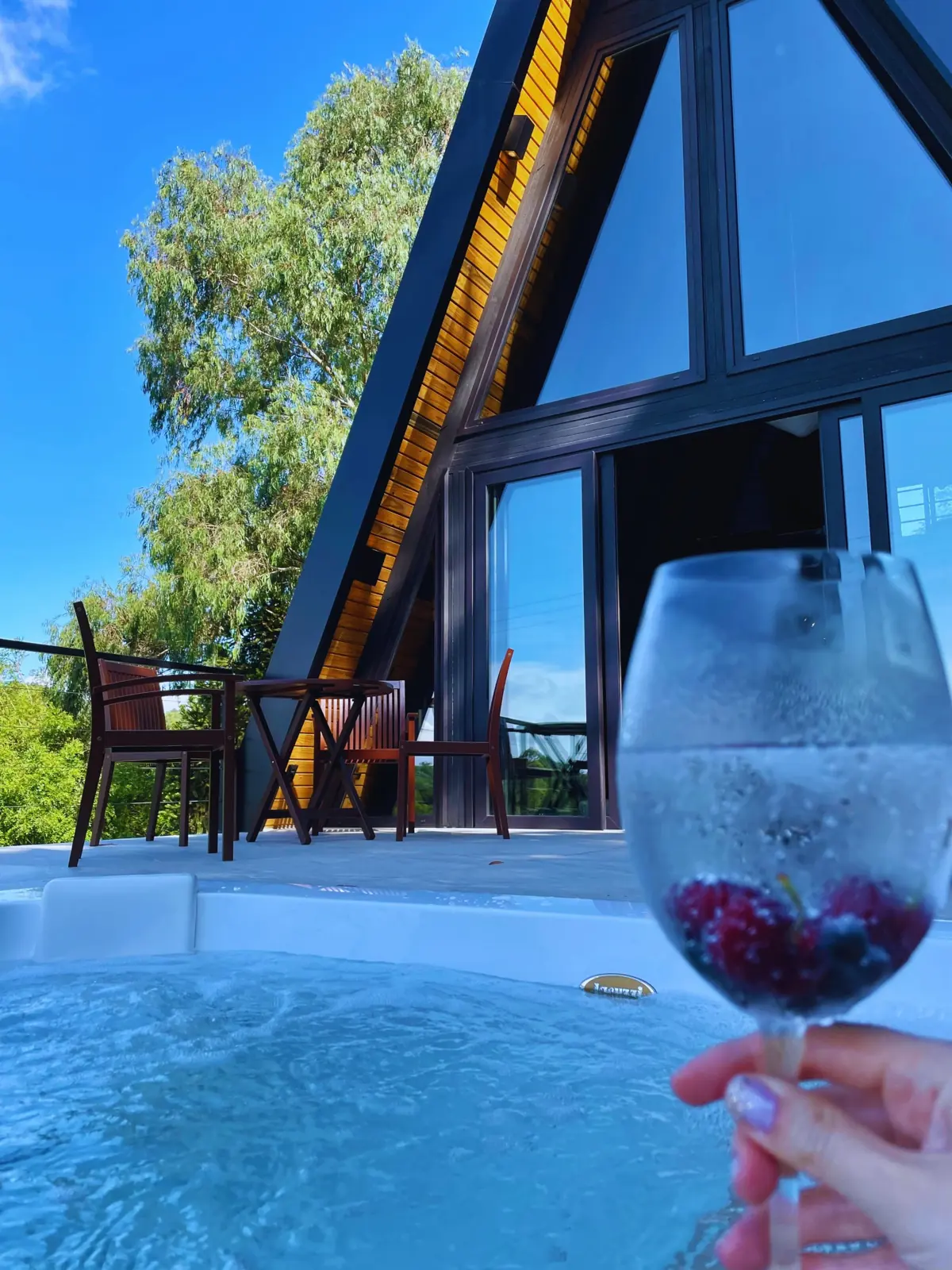 Jacuzzi aquecida com hidromassagem em frente à cabana, em dia de sol
