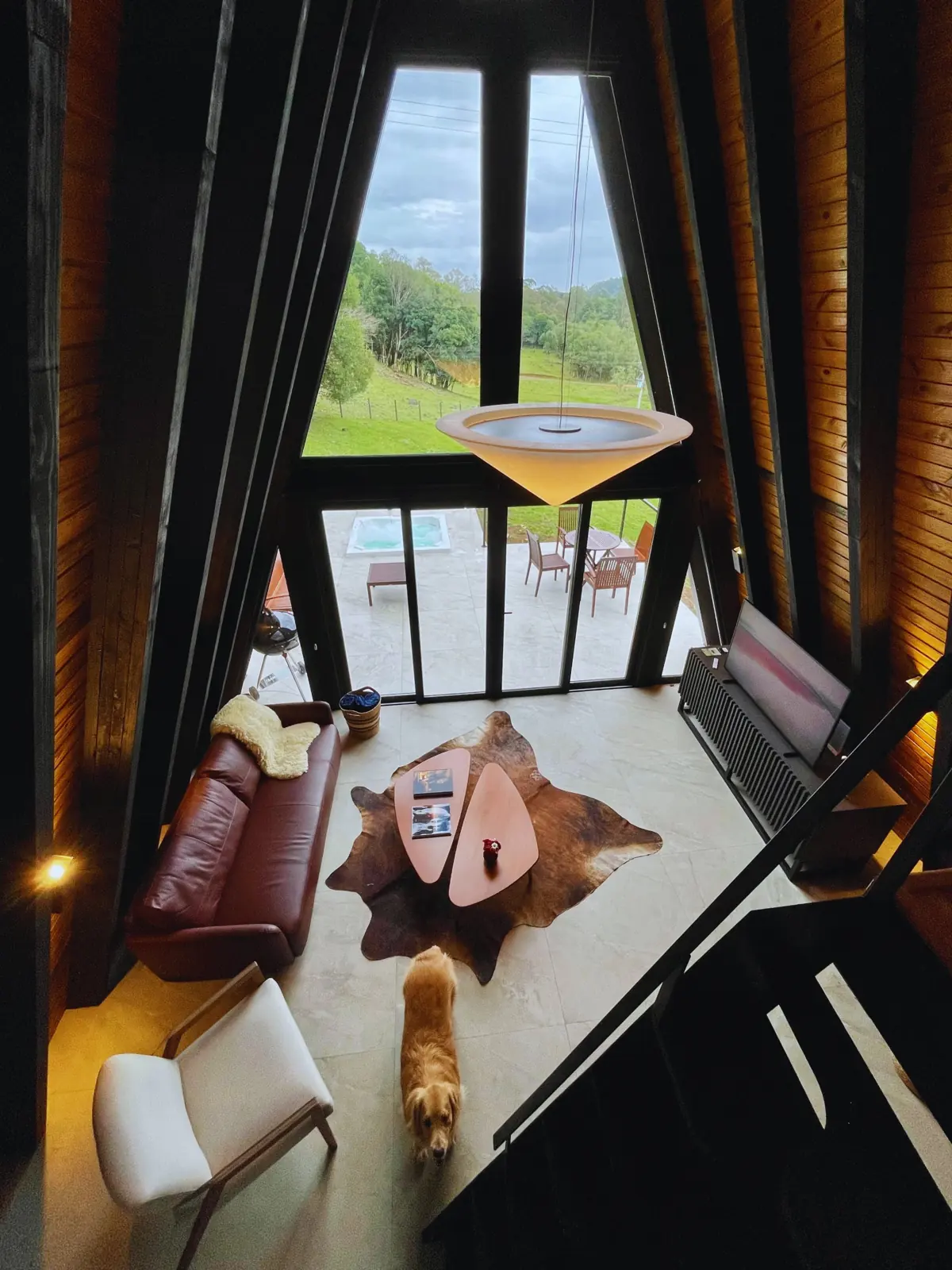 Sala vista de cima, com tapete de couro, mesa de centro e o deck ao fundo
